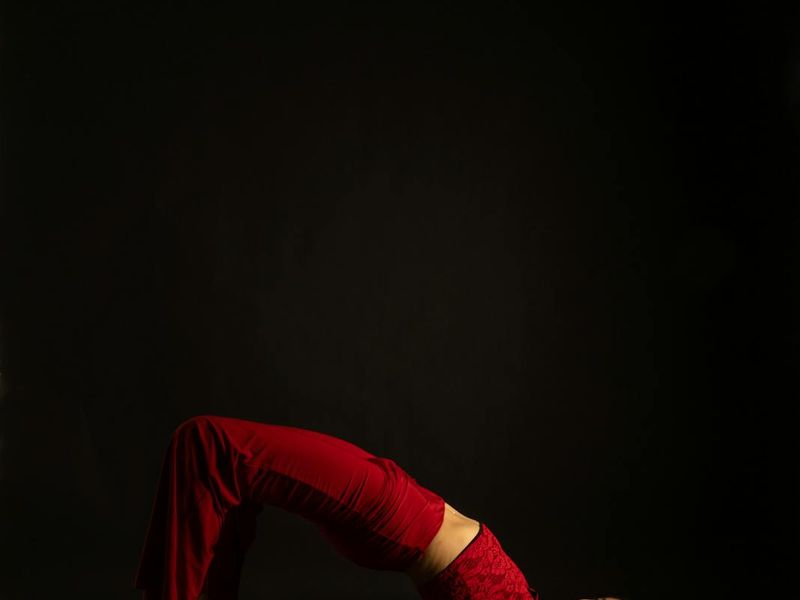 Person performing a smooth yoga movement in a dark studio.